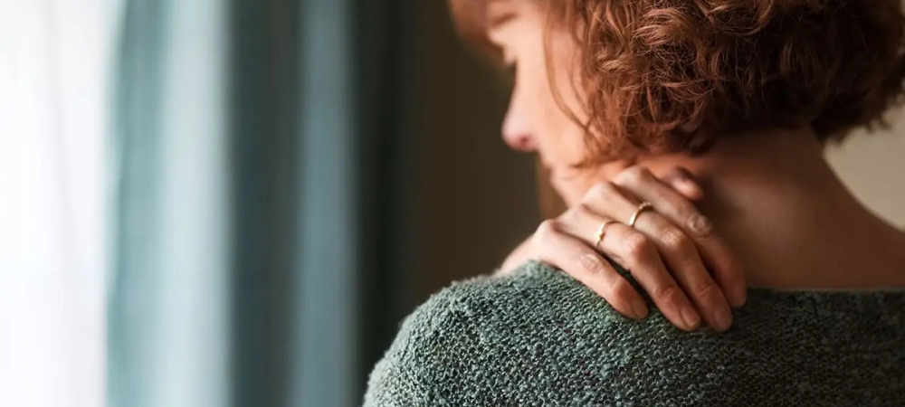 woman rubbing shoulder in pain