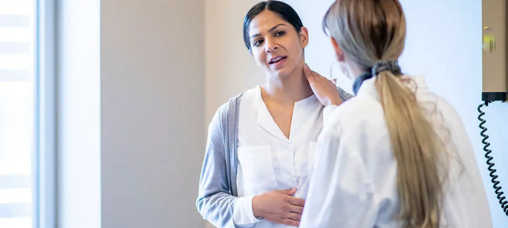 woman with hand on neck talking to doctor