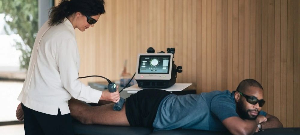 clinician applying laser to patient's upper thigh